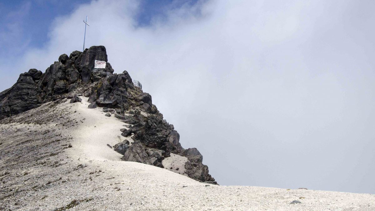 A cross rises above a peak at Guagua Pichincha