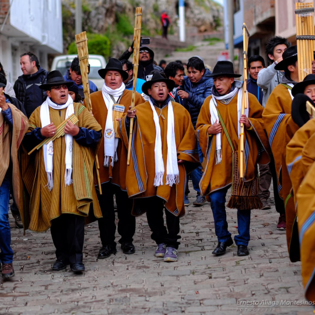 Singers dressed in dark yellow ponchos descend to a street to start the festivities