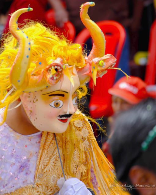A Chinese devil wears a mask with giant yellow horns and bright yellow hair