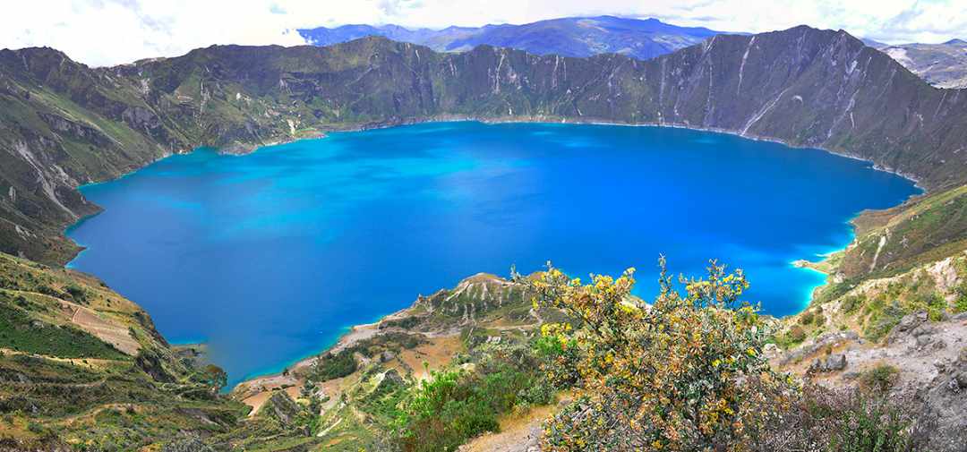 Brilliant blue crater lake surrounded by green mountains