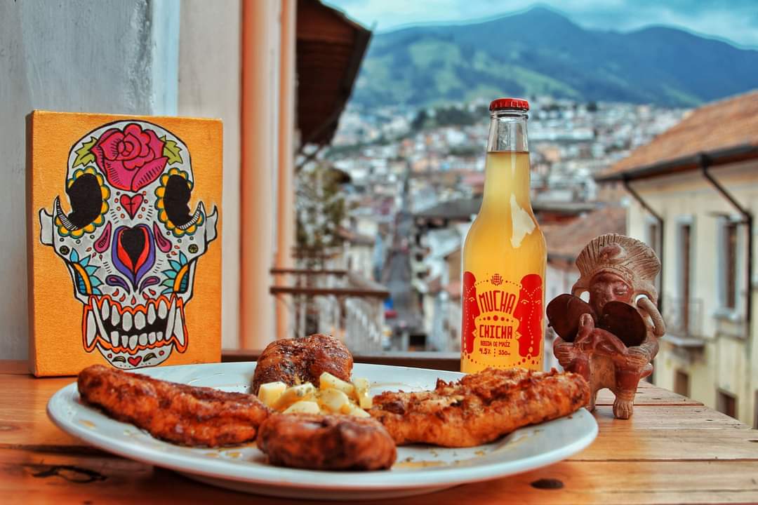 Comida Típica in Barrio La Tola with a View of Historic Quito, Ecuador | ©Sereno Moreno Picantería Plate of food, bottle of chicha, and view of historic Quito