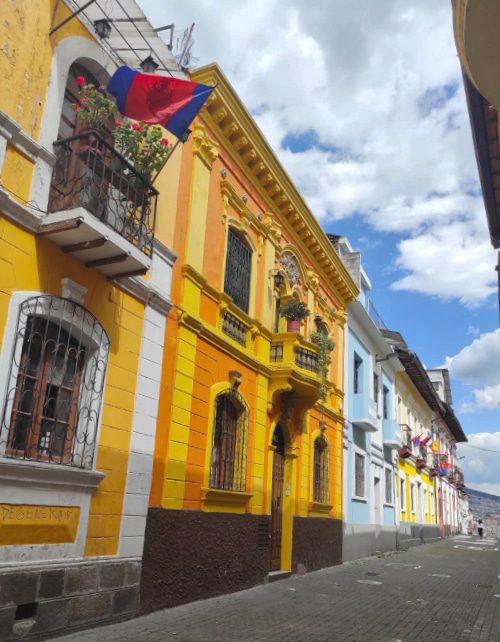 An old house painted bright orange with yellow accents next to other old houses