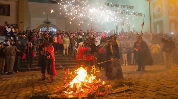 Fire Blessing People dressed as devils stand around a fire in the center of a church plaza in Alangasi, Ecuador