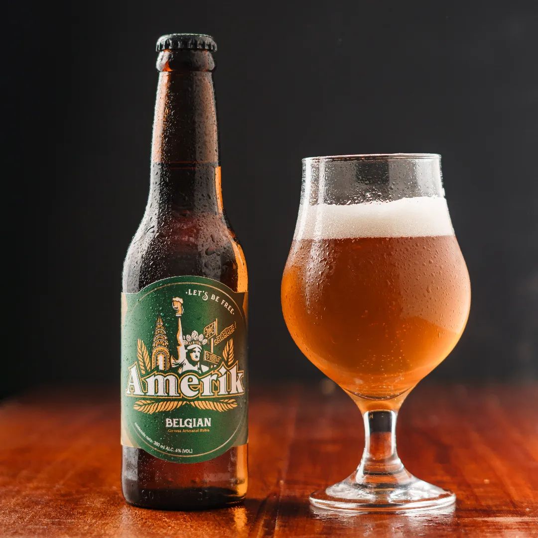 Belgian Blond Saison by Amerik A bottle of Blond Belgian Beer stands alongside a glass of deep gold beer with thick head of foam,