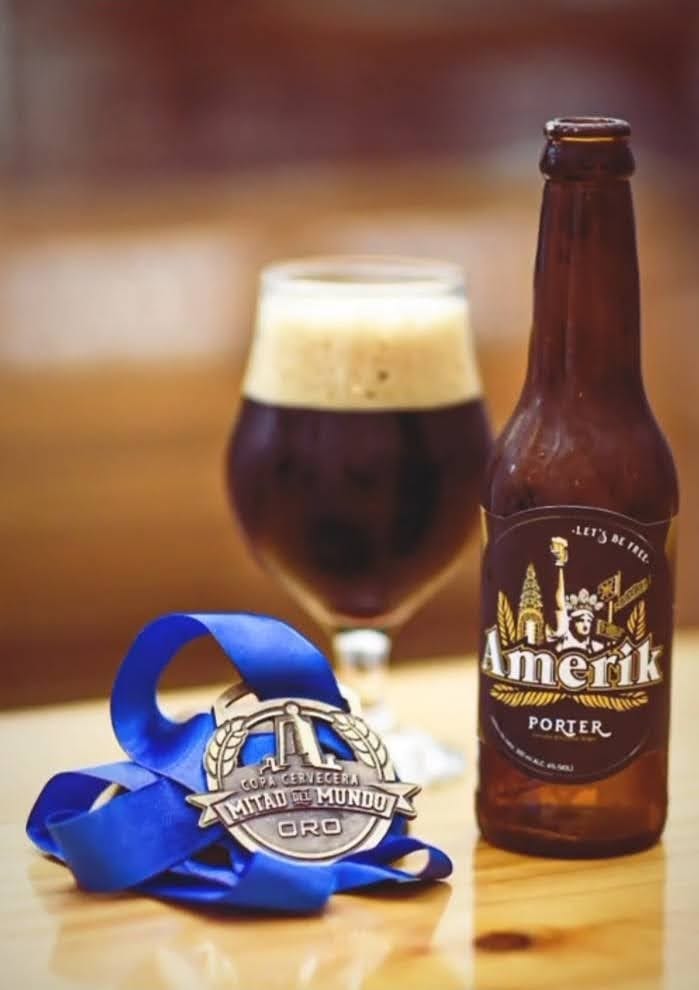 Una botella de Porter se encuentra junto a un vaso de cerveza marrón espresso con una gruesa cabeza de espuma y una medalla de oro con cinta azul