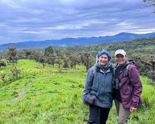 Julia Patiño and a client pose for the camera while birdwatching open fields near Refugio Paz