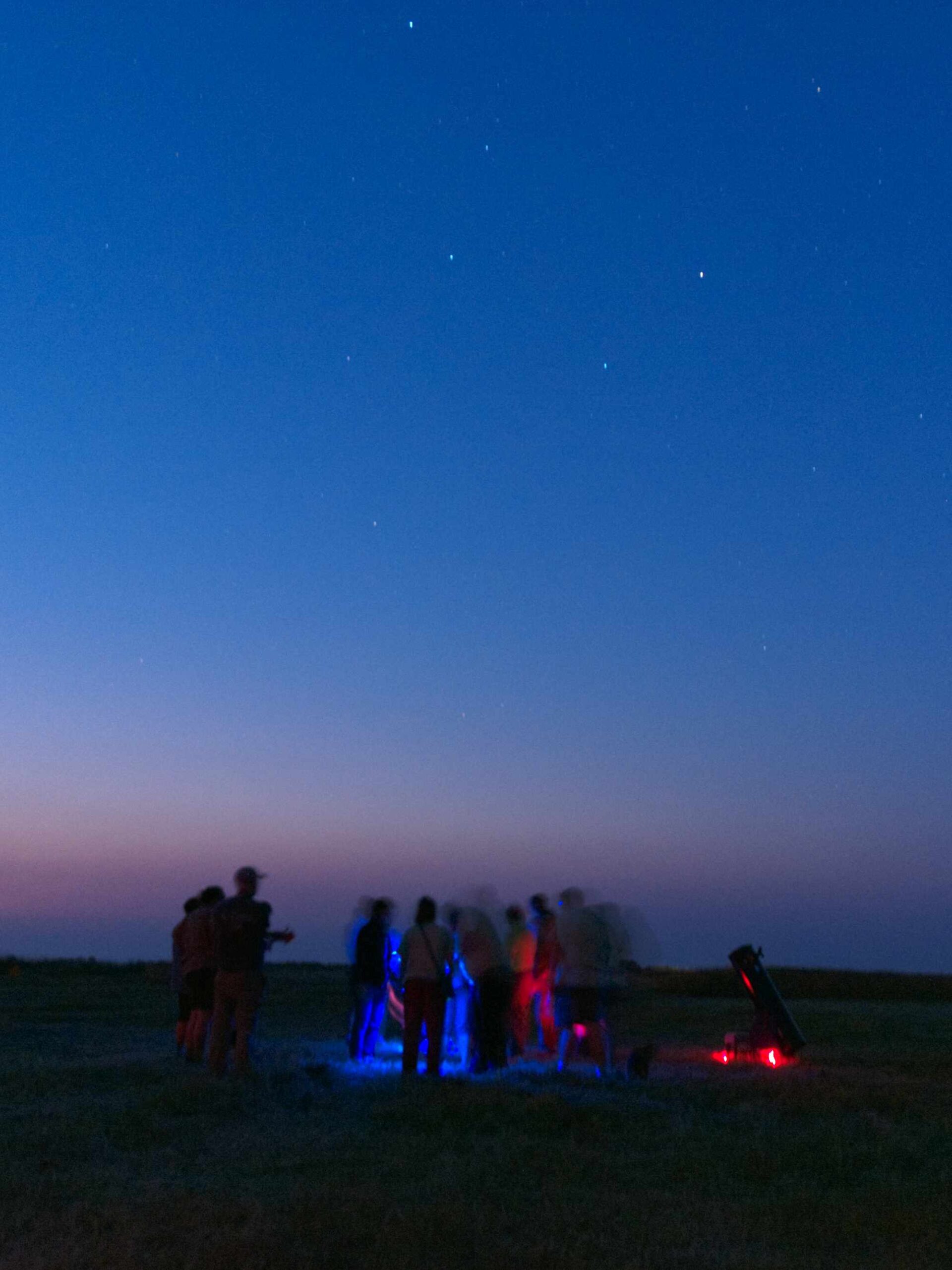 Families playing with light with OMSI rep as twilight fades to night sky.