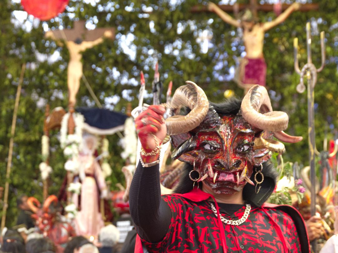 A masked man appears as a devil in Alangasí's church on Good Friday