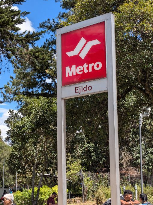 The distinctive Quito Metro Signs are bright red with white lettering and a track swoop icon.