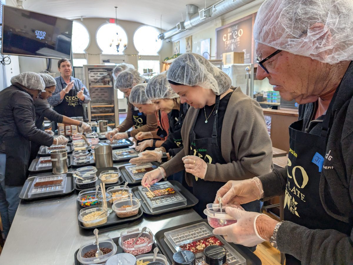 A class of chocolate apprentices hard at work adding ingredients to liquid chocolate.