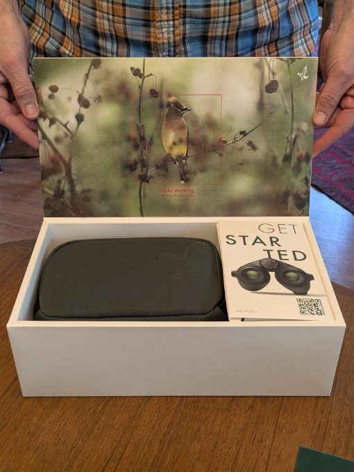 Scott opening the AX Visio A pair of hands holds the top of a box open to display its contents: a set of AX Visio Smart Binoculars