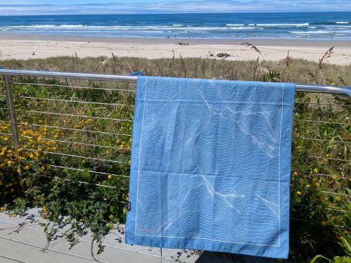 A Laek Adventure Towel hanging from a fence on the Oregon Coast.