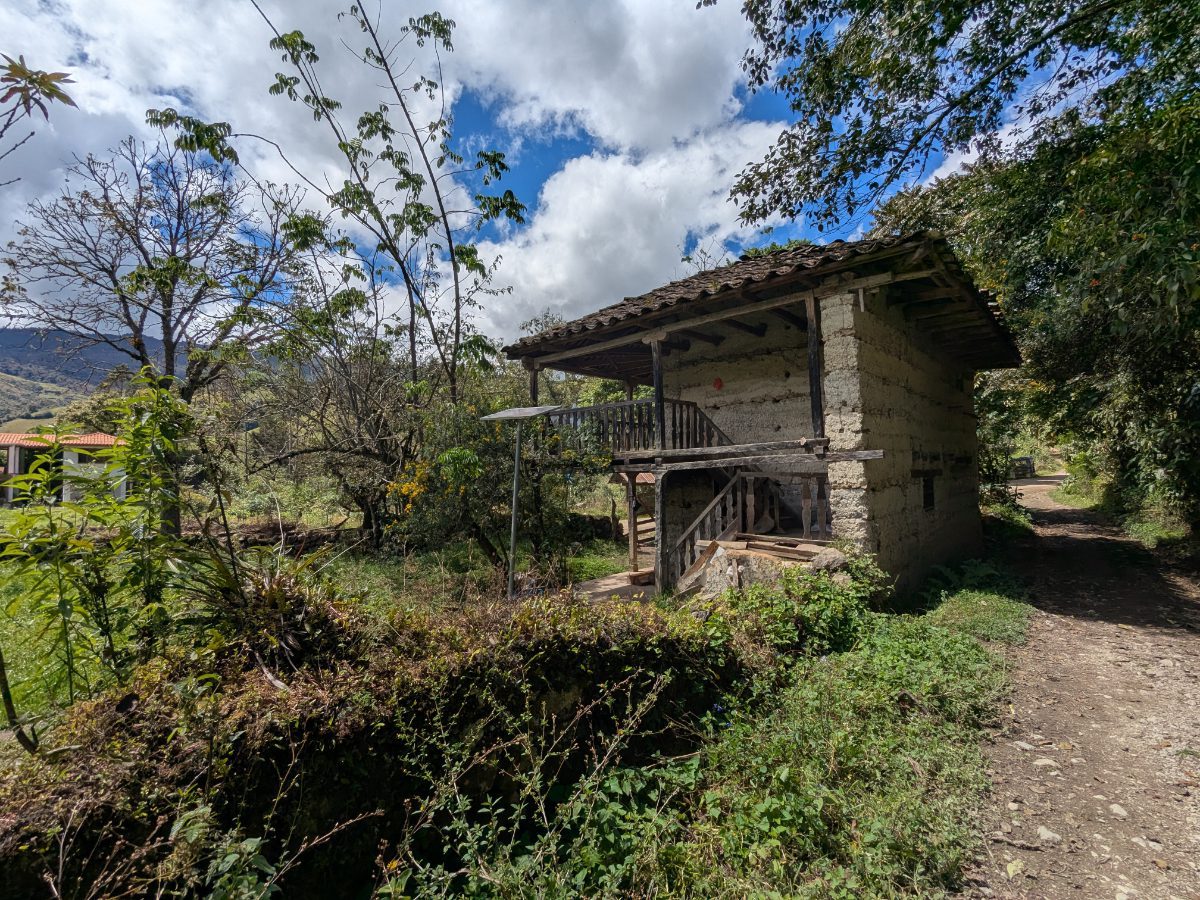 A dab and wattle building with tile roof and wooden stair rails and balcony along the Leymebamba community trail.