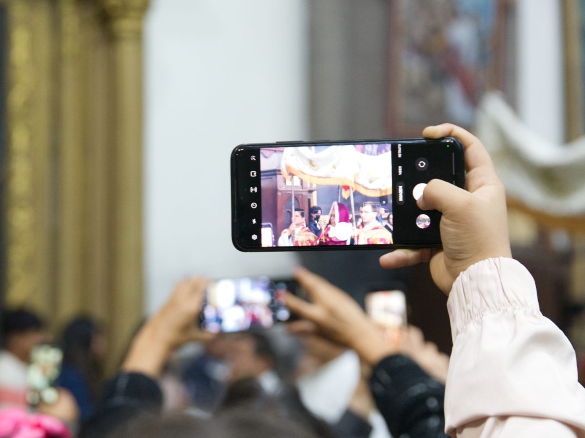 The Archbishop of Quito in the Arrastre de Caudas procession as seen through the cellphones of the person in front of the photographer.