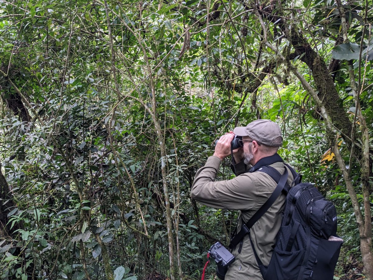 Scott hiking in the forest wearing the Aero Jet backpack while searching for birds with binoculars