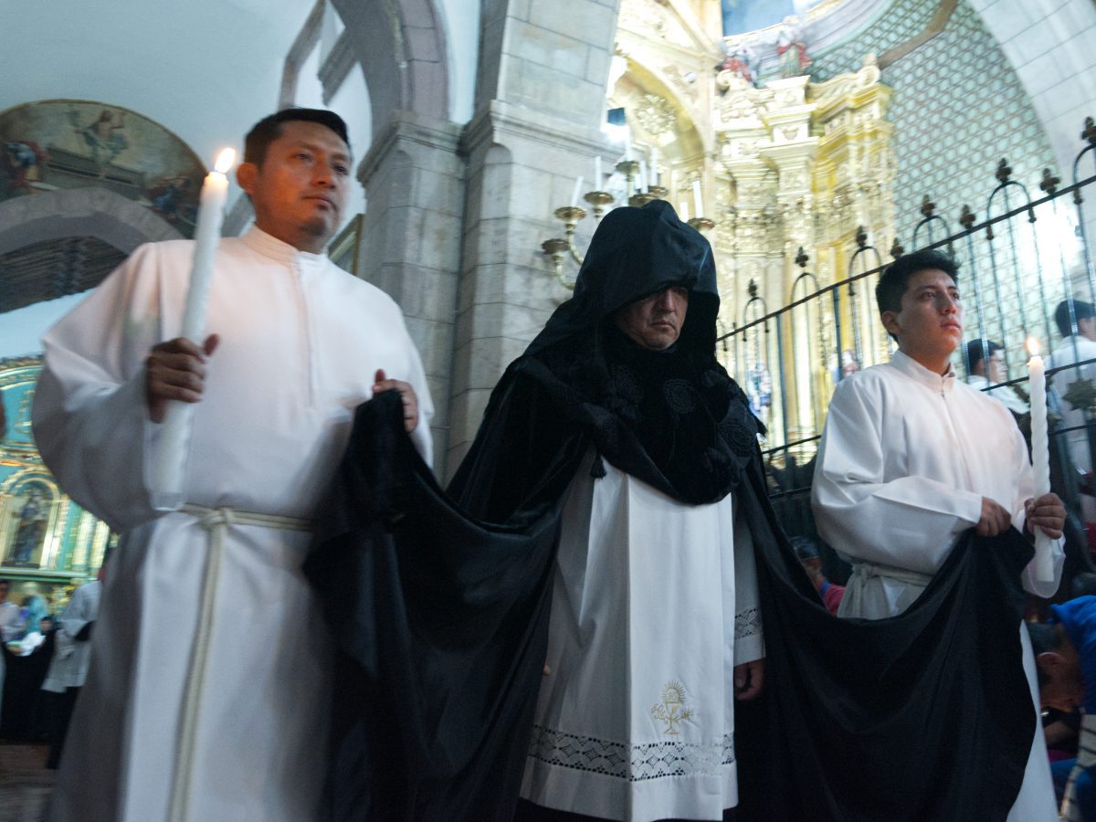 Canon in procession with two white-robed attendants holding candles, Arrastre de Caudas Quito Ecuador