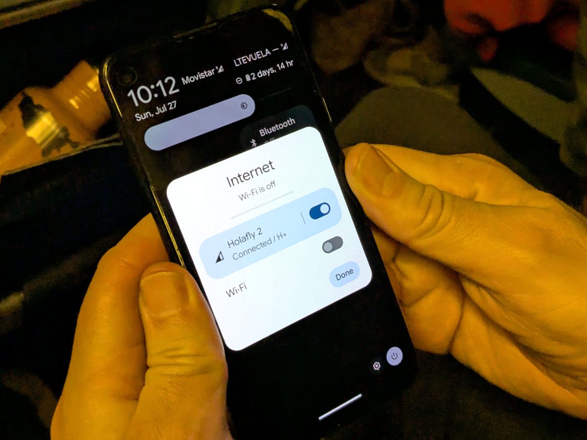 Hands hold a phone showing an internet connection using the HolaFly eSim.