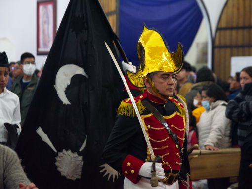 A man dressed as a soldier carries a black flag with an image of the moon and stars.
